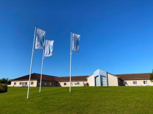 three flags in a field in front of a building at Hotel Højbysø in Højby
