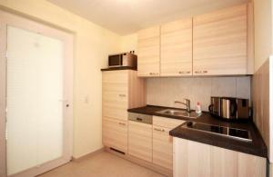 a kitchen with wooden cabinets and a sink at Strandschloesschen-Haus-II-WE-11-9644 in Kühlungsborn