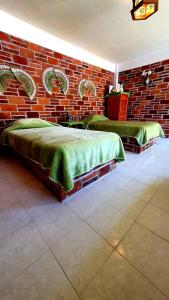 two beds in a room with a brick wall at Hotel Casa de la Luna in San Juan Teotihuacán