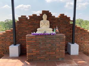 a buddha statue sitting on a brick wall at Monaara Leisure - Anuradhapura in Anuradhapura