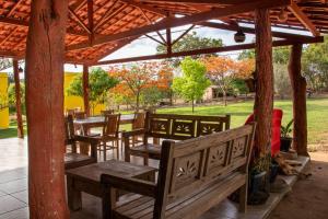 a row of wooden tables and benches under a pavilion at Pousada Chalés Praia Vermelha in São João Batista do Glória