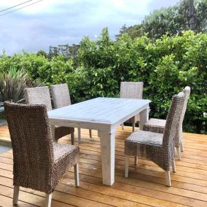 a white table and chairs on a wooden deck at Mangawhai Room in Mangawhai