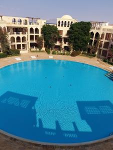 Gorgeous Pool View Apartment - Tala Bay Resort, Aqaba في العقبة: مسبح أزرق كبير أمام مبنى