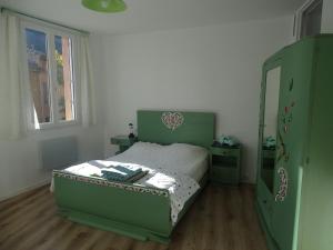 a bedroom with a green bed and a window at Appartement spacieux 6 personnes très lumineux in Buis-les-Baronnies