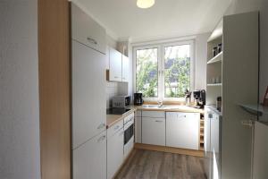 キュールングスボルンにあるHaus-Amber-Mare-Strandtraeumer-9695の白いキャビネットと窓付きのキッチン