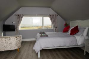 a bedroom with a bed with red pillows and a window at Atlantic Sunset in Portmagee