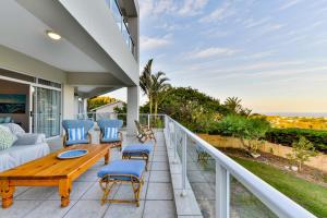 a patio with a wooden table and chairs on a balcony at Plettenberg View in Plettenberg Bay