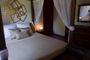 a bedroom with a large white bed with curtains at LA KAZ KRÉOL in Cayenne