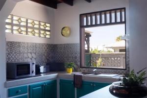 a kitchen with a sink and a microwave and a window at La KAZ KRÉOLE in Cayenne
