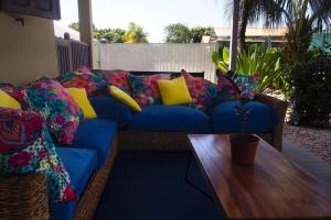 eine blaue Couch mit bunten Kissen und einem Holztisch in der Unterkunft LA KAZ KRÉOL in Cayenne