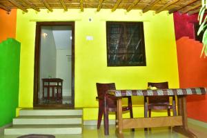 a table and chairs in front of a yellow wall at Megha Resort , Hampi in Hampi
