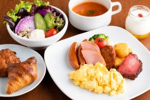 a table with plates of breakfast foods and a cup of tea at JR Kyushu Hotel Blossom Shinjuku in Tokyo