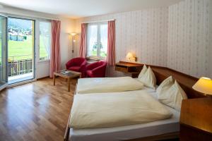 ein Hotelzimmer mit einem Bett und einem Stuhl in der Unterkunft Hotel Berghaus in Wengen