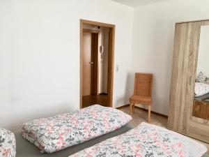 Cette chambre comprend deux lits, une chaise et un miroir. dans l'établissement Ferienwohnung im Zentrum von Sonneberg, à Sonneberg