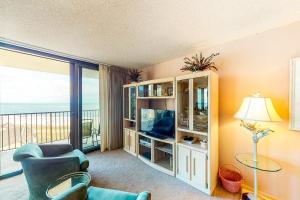a living room with a television and a balcony at Sea Colony Chesapeake House III in Bethany Beach
