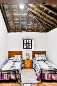 CASA VILA في Garafía: سريرين في غرفة نوم ذات سقف خشبي