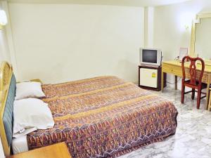 a bedroom with a bed and a desk and a television at Highfive Guest House in Pattaya Central