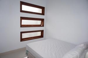 a white room with two windows and a bed at Cemara Homestay Jogja in Yogyakarta