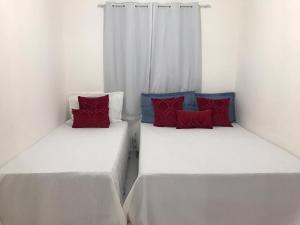 2 bedden met rode en blauwe kussens in een kamer bij FLAT PRAIA DOS CARNEIROS / TAMANDARÉ 06 TÉRREO in Recife