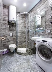 ein Bad mit einer Dusche, einem WC und einer Waschmaschine in der Unterkunft Апартаменти "Kopernik" in Kiew