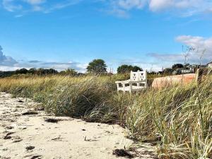 a white bench sitting in the grass next to a beach at 4 person holiday home in S nder Stenderup in Sønder Stenderup