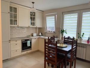 a kitchen with white cabinets and a table and chairs at Apartament Stylowy Pruszków Centrum in Pruszków
