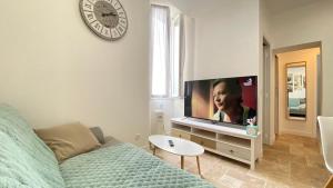 uma sala de estar com um sofá e uma televisão de ecrã plano em Cosy 3 Pièces Vue Mer Aux Parfums de Grasse em Grasse