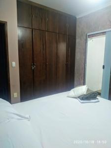 a bedroom with a large white bed with a wooden cabinet at POUSADA DONA DORA 2 in Piumhi