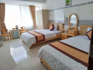 a hotel room with two beds and a mirror at Khách Sạn Flower Sky Nha Trang in Nha Trang