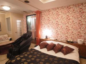ein Schlafzimmer mit einem Bett und einem Stuhl in einem Zimmer in der Unterkunft Hotel VINO Adult Only in Kawaguchi