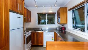 a kitchen with a white refrigerator and wooden cabinets at Kimberley Two - Nelson Waterfront Apartment in Nelson