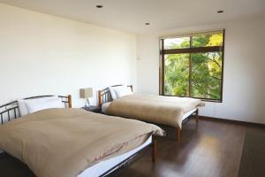 two beds in a room with a window at The Little Garden in Miyazaki