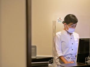 uma mulher usando uma máscara facial na frente de um computador em Maki No Oto Kanazawa em Kanazawa