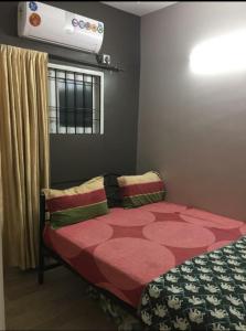 a bedroom with a bed with a red comforter and a window at Avvairam Service Apartment - C9 in Chennai