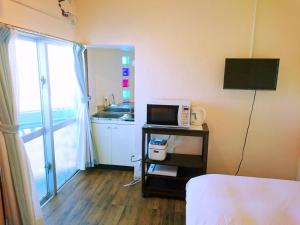 Habitación de hotel con microondas y cocina. en Eef Condominium Kumejima, en Kumejima