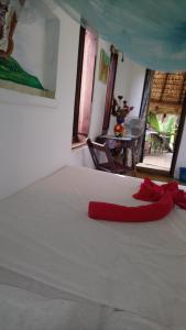 una camera da letto con un letto bianco con un nastro rosso sopra di Castillo Oasis a Zipolite