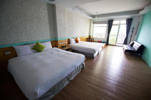 una camera d'albergo con due letti e un divano di 荷風民宿 a Eluan