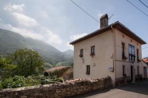ein Haus auf einem Hügel mit einer Steinmauer in der Unterkunft Casa del Cuetu. Traditional village house in Asturias in Meré