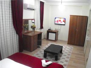 a room with a bed and a desk and a tv at Alize Resort Hotel in Yenifoça