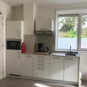 a kitchen with white cabinets and a window at Hendrikhof - appartement 1 ‘de Tas’ in Westkapelle
