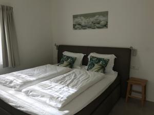 a large bed with white sheets and pillows on it at Hendrikhof - appartement 1 ‘de Tas’ in Westkapelle