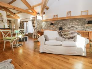 a living room with a white couch and a stone wall at The Cow House in Penrith