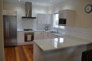 cocina con armarios blancos y nevera de acero inoxidable en Villa 185- Central Masterton en Masterton
