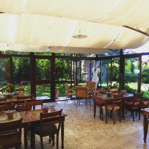 un restaurante con mesas y sillas de madera y ventanas en B&B Villa Acero en Marina di Carrara