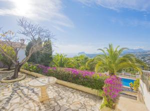 a patio with a table and flowers and a pool at Villa Alondra - Plusholidays in Moraira