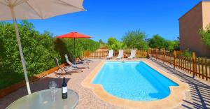 einen Pool mit einem Tisch und einem Sonnenschirm in der Unterkunft Finca Can Olivaret 419 by Mallorca Charme in Campos
