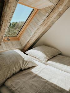two beds in a attic room with a window at Las Skarpa apartamenty in Srebrna Góra