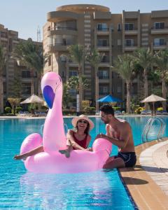 a man and a woman sitting on an inflatablevisor in a pool at Grand Ocean El Sokhna in Ain Sokhna