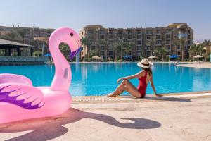 a woman sitting next to a pink swan in a pool at Grand Ocean Sokhna Hotel & Resort in Ain Sokhna