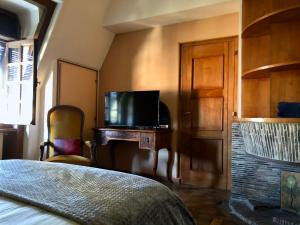 Schlafzimmer mit einem Bett und einem TV auf einem Schreibtisch in der Unterkunft Le Logis d'Arniere in Saint Cyr-sous-Dourdan